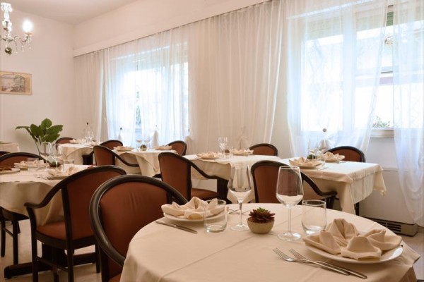 Elegantne prestretá jedáleň s okrúhlymi stolmi a stoličkami, zdobená svetlými obrusmi a pohármi.