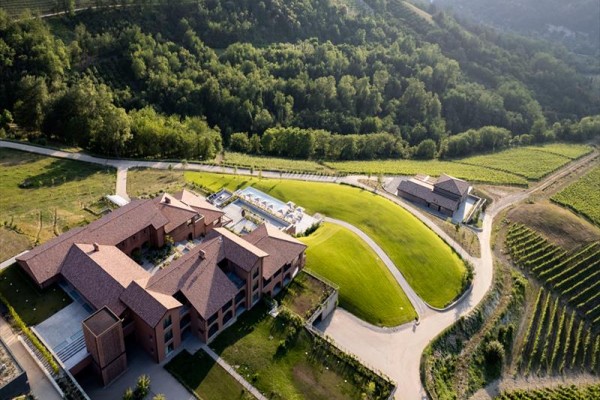 Vinárstvo s modernými budovami obklopené vinicami a lesmi.  