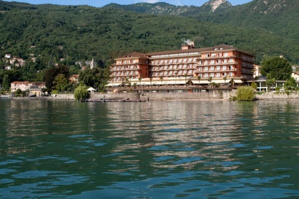 Veľký hotel pri jazere s horami v pozadí.  