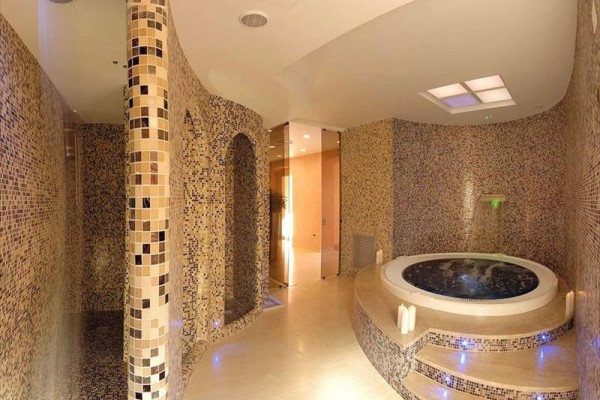 Luxusný interiér spa s vírivkou a stenami obloženými mozaikovými dlaždicami.