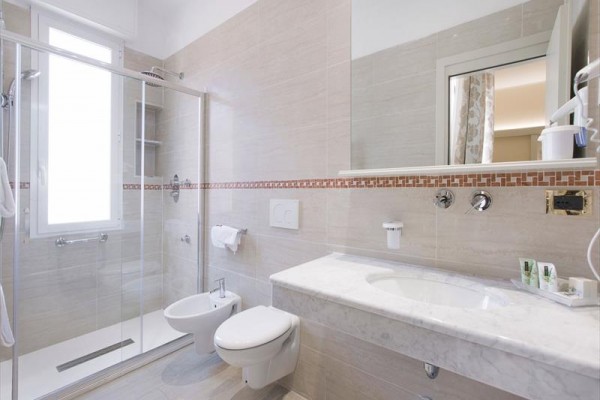 Moderná kúpeľňa s preskleným sprchovacím kútom, závesným WC a umývadlom.