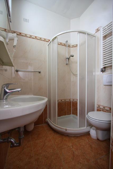 Malá kúpeľňa so sprchovacím kútom, umývadlom a toaletou.