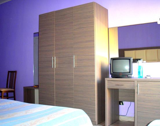 Izba s fialovými stenami, skriňou, televízorom na stole a stoličkou.