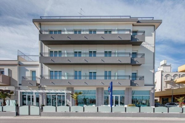 Štvorposchodová moderná budova s balkónmi a veľkými oknami.