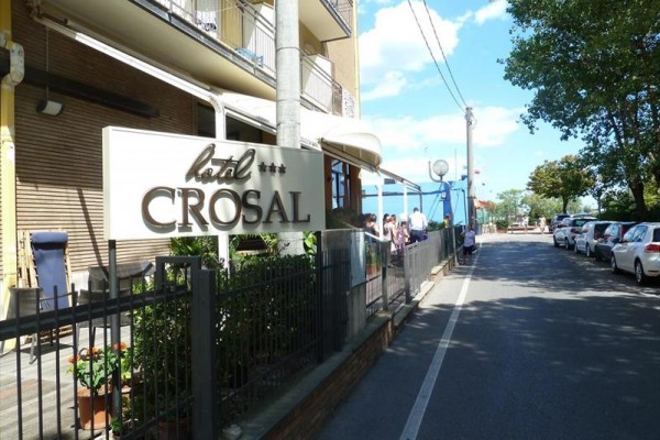 Značka hotela Crosal pri ceste s autami a stromami.
