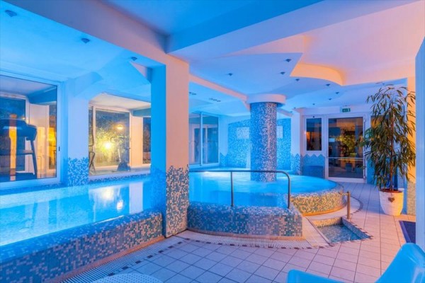 Interiér wellness centra s bazénom osvetlený modrým svetlom.
