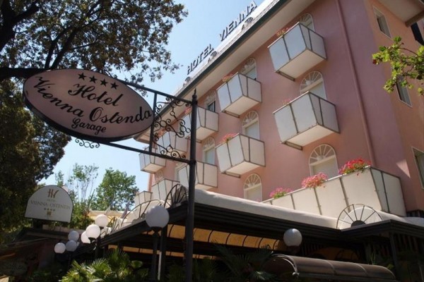 Ružový hotel s balkónmi a tabuľou označujúci päťhviezdičkový Hotel Vienna Ostenda.