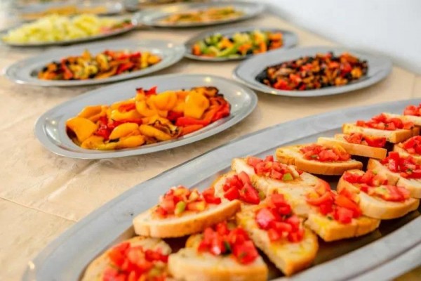 Taniere s rôznymi predjedlami, v popredí bruschetta s paradajkami.  