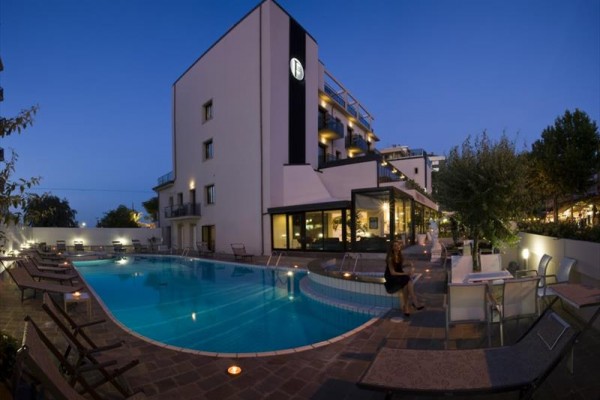 Luxusný hotel s vonkajším bazénom pri súmraku.
