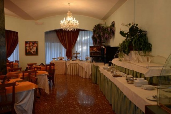 Elegantná jedáleň s lustrom, závesmi a bufetovým stolom.