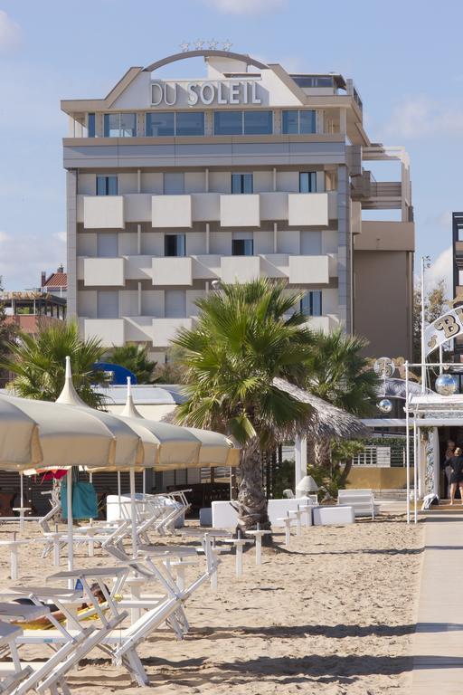 Plážový pohľad s palmami a ležadlami pred hotelom DU SOLEIL.