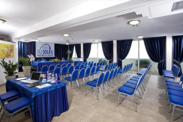 Konferenčná miestnosť s modrými stoličkami a stolom pokrytým modrou látkou.