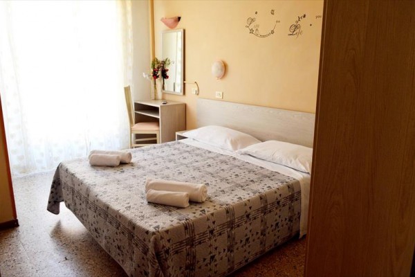 Spálňa s manželskou posteľou, dvoma uterákmi a pracovným stolom blízko okna.