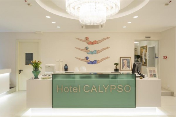 Recepcia hotela Calypso s moderným osvetlením a dekoráciou plavcov na stene.