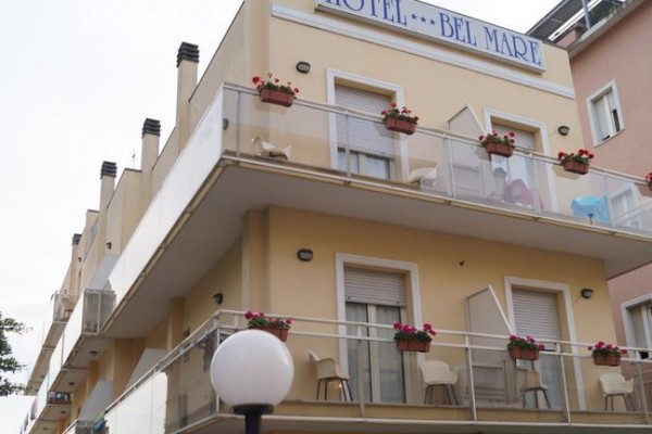 Trojposchodová budova hotela Bel Mare s balkónom ozdobeným kvetmi.  