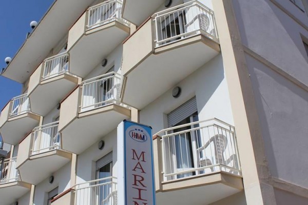 Budova hotela s viacerými balkónmi a nápisom 