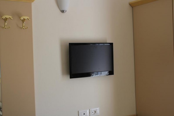 Televízor zavesený na béžovej stene medzi skrinkami.