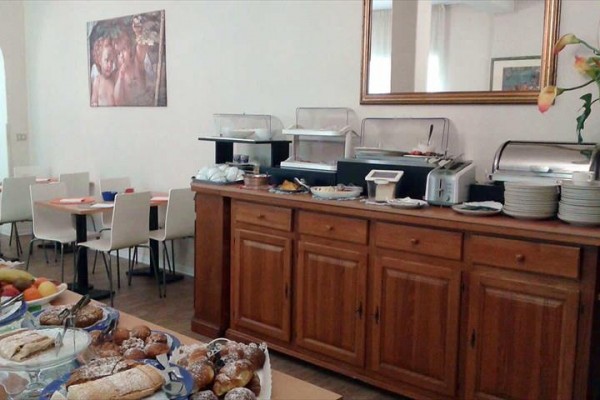 Hotelová raňajková miestnosť s bufetovým stolom a rôznymi druhmi pečiva.