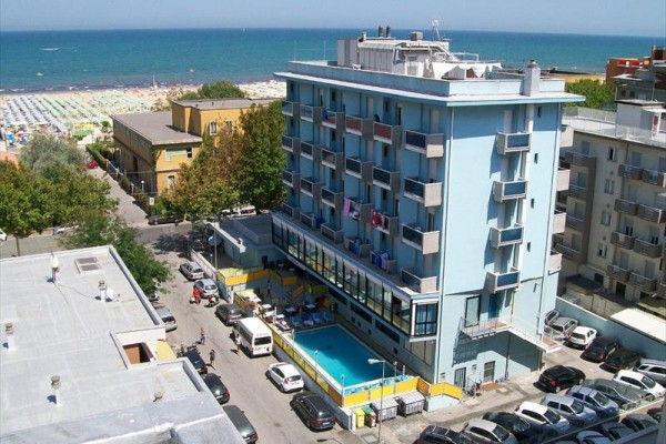 Modrý hotel s bazénom blízko pláže a mora.