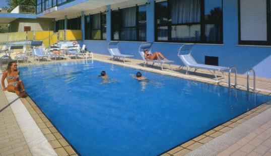 Vonkajší bazén s niekoľkými ľuďmi, ktorí relaxujú a plávajú.