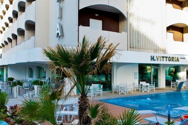 Moderný hotel so skleneným oplotením a malým bazénom pri vchode.