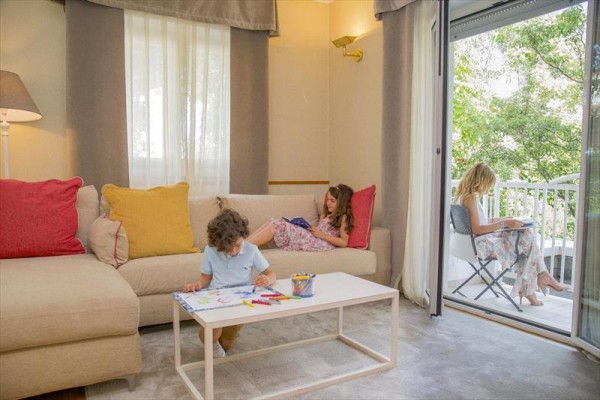 Tri deti relaxujú a kreslia v obývacej izbe a na balkóne.