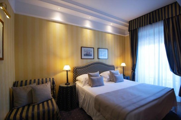 Elegantne zariadená hotelová izba s dvoma lampami a manželskou posteľou.