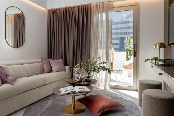 Moderná obývačka s pohovkou, zlatým konferenčným stolíkom a prístupom na balkón.