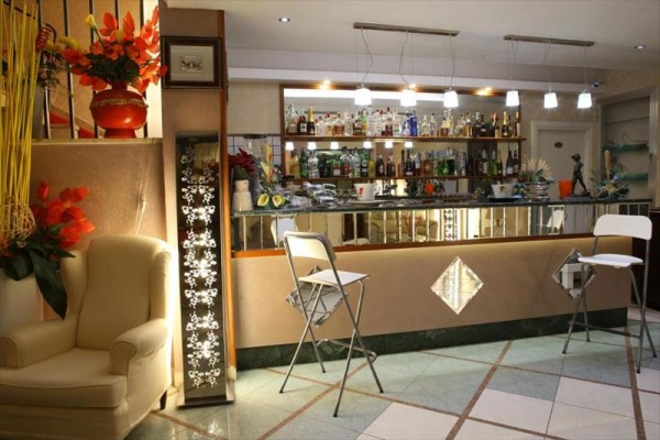 Moderný bar s rôznymi fľašami alkoholu a vysokými stoličkami, doplnený výraznou dekoráciou.