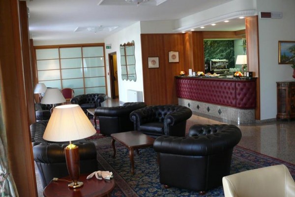 Elegantná hotelová lobby s koženými kreslami a recepciou.