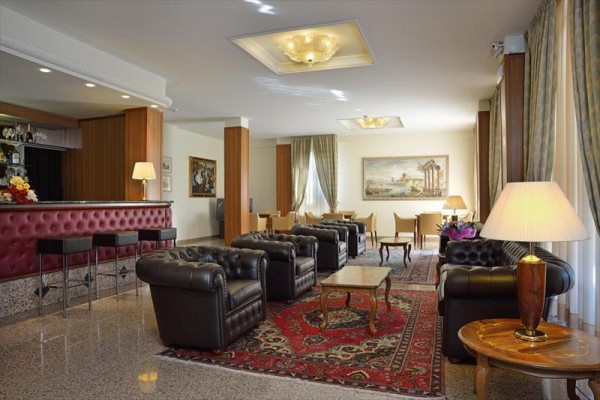 Elegantná hotelová lobby s koženými pohovkami, kobercami a barom.