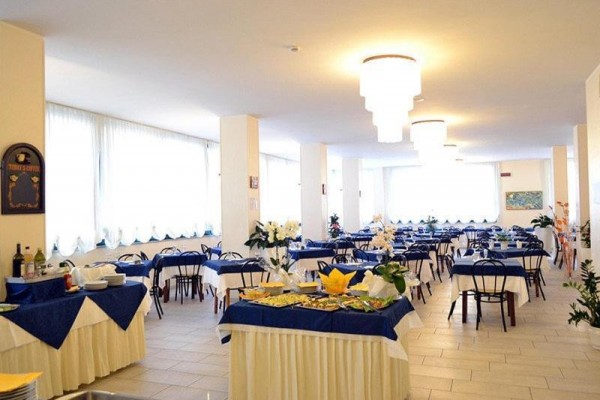 Svetlá reštaurácia s modrobielymi obrusmi a stolmi pripravenými pre hostí.