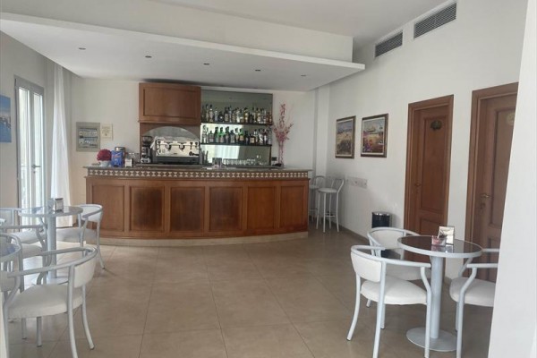 Malý bar s dreveným pultom obklopený niekoľkými stolmi a stoličkami.