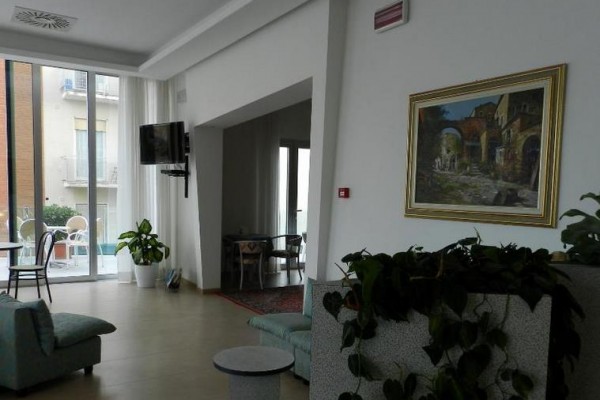 Moderný obývací priestor s obrazmi na stene a rastlinami s výhľadom na balkón.