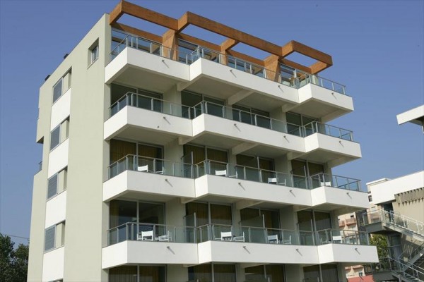 Moderná budova s balkónmi a drevenou konštrukciou na streche.