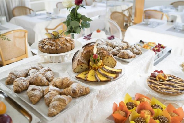 Stôl s rôznymi dezertmi, ako sú croissanty, koláče a muffiny, v jedálni.