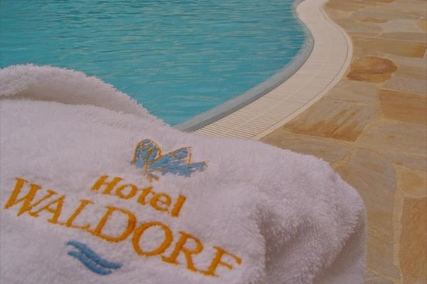Biely uterák s logom Hotel Waldorf pri bazéne.  