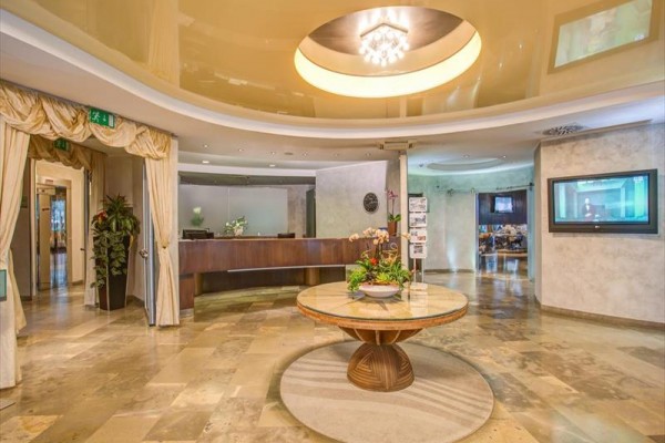Luxusná hotelová vstupná hala s okrúhlym stolom a recepciou.