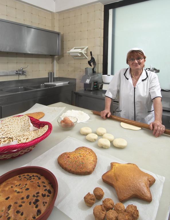 Žena v kuchyni pripravuje pečivo s rôznymi tvarmi cesta na pracovnom stole.