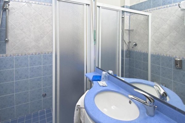 Modro-biela kúpeľňa s umývadlom a sprchovacím kútom s posuvnými dverami.  