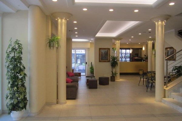 Hotelová hala s pohovkou, recepciou a rastlinami.