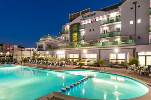 Hotel s osvetleným bazénom v noci.  