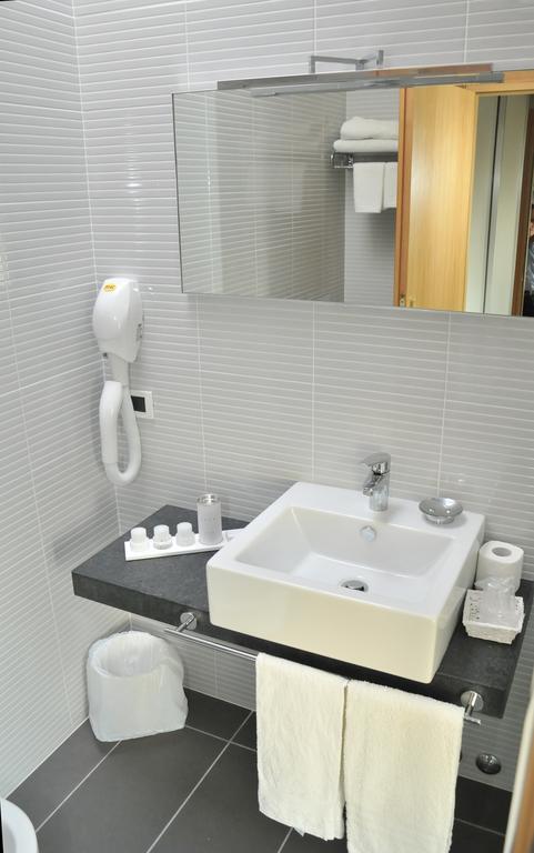 Moderná kúpeľňa s bielym umývadlom, zrkadlom a sušičom na vlasy.