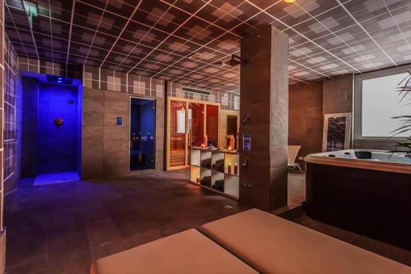 Wellness priestor s vírivkou, sprchou a saunou s jemným osvetlením.