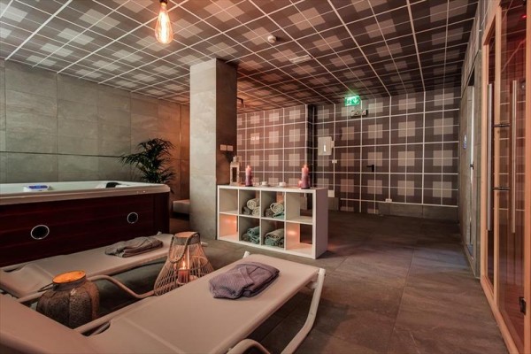 Wellness miestnosť s lehátkami, vírivkou a saunou v modernom štýle.  