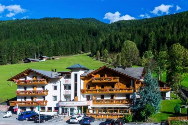 Hotel v horskej krajine obklopený lesmi a lúkami.