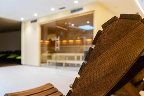 Drevené lehátko v priestore pred presklenou saunou.