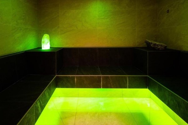 Parná sauna s čiernymi lavicami a zeleným osvetlením.
