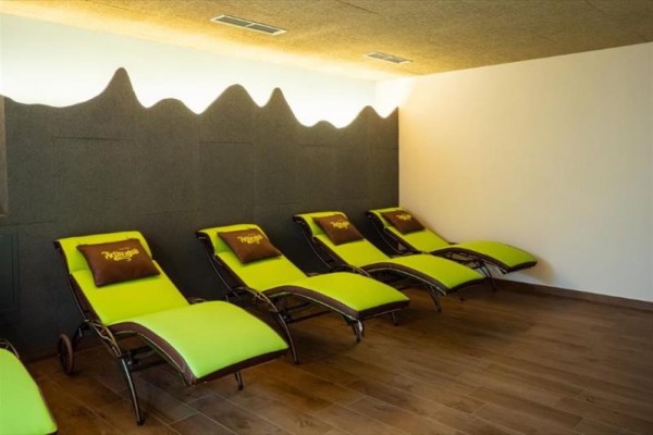 Relaxačná miestnosť s piatimi zelenými lehátkami a drevenou podlahou.  