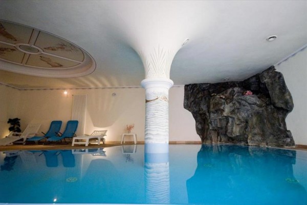 Vnútorný bazén s lehátkami a dekoračnou skalou.